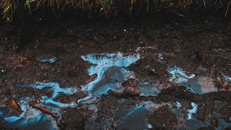 Smudges of toxic Industrial liquid chemical pollutant visible on surface of soil