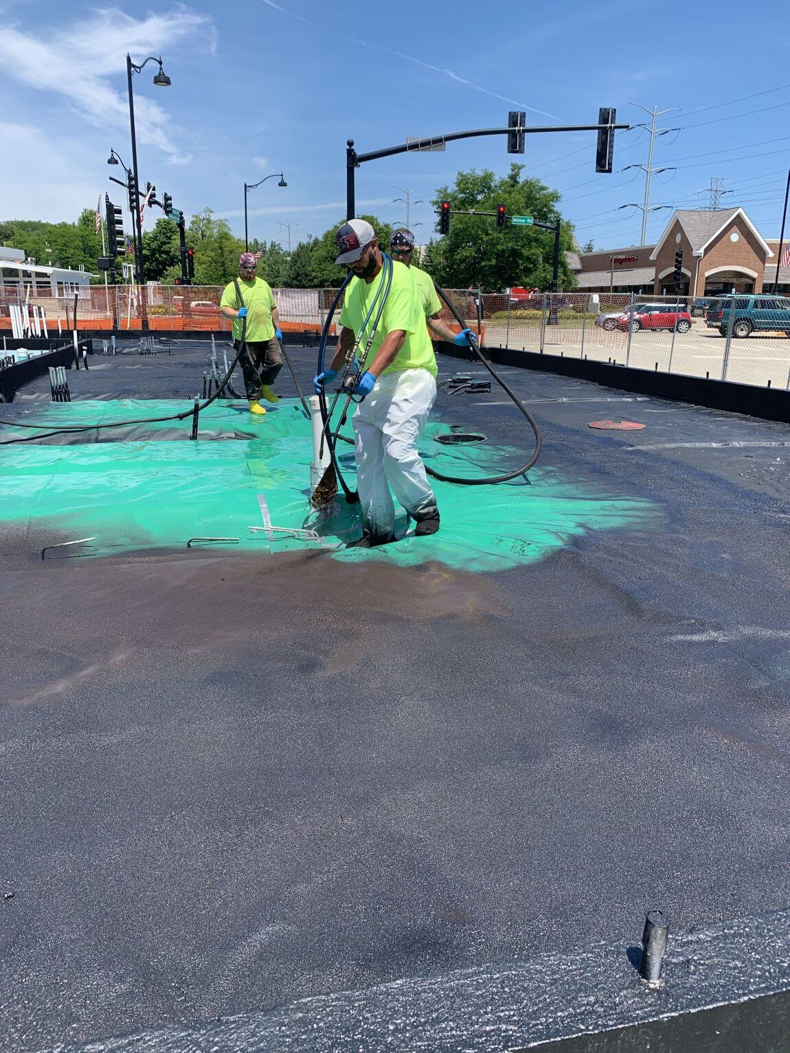Cabeno team installing vapor barrier on construction site, including green top layer